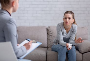 Psychological help service. Depressed female patient having psychotherapy session with counselor at office. Young woman with emotional or family problems consulting mental health professional